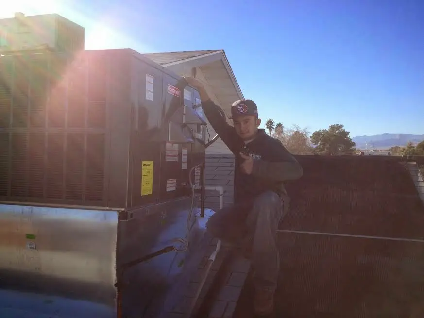 HVAC technician performing Heat Pump Repair on a rooftop unit in Shelton